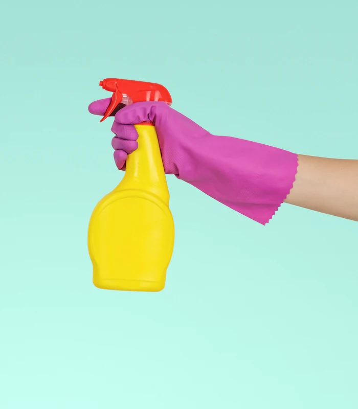 Gloved hand holding a cleaning spray bottle